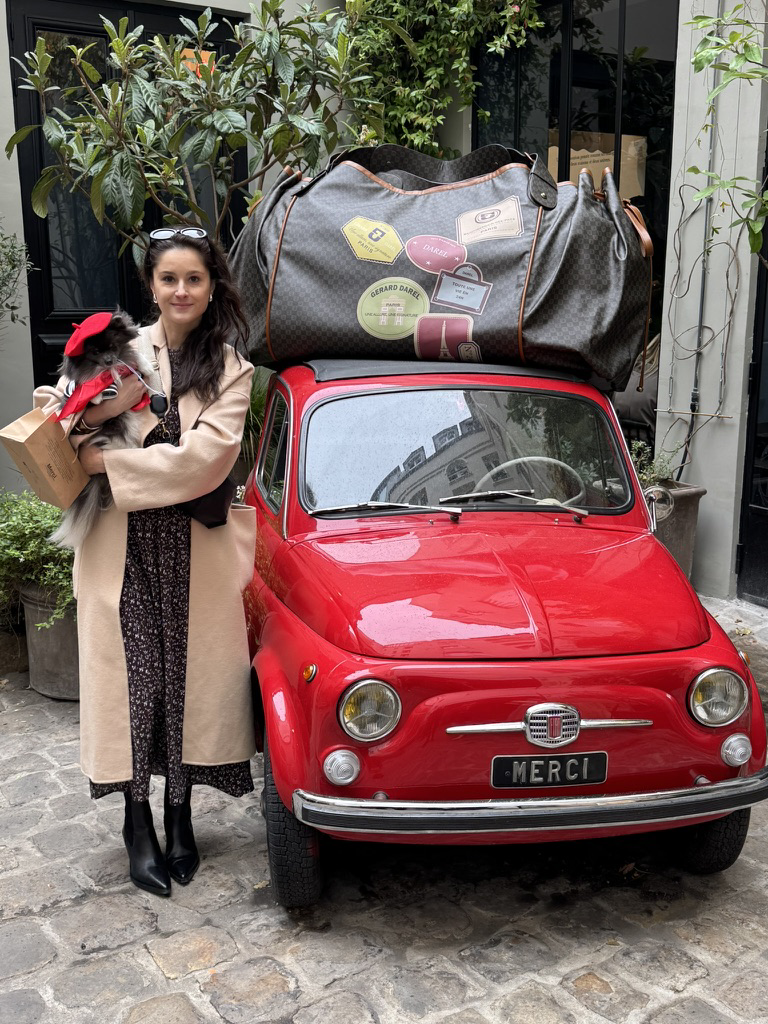 Amanda holding the puppy beside the red Merci car