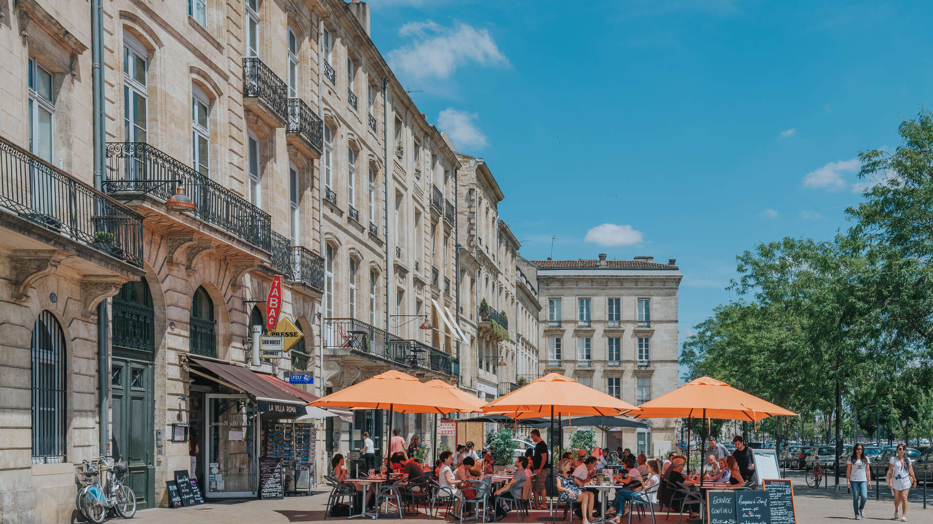 A café terrace beneath orange umbrellas in Bordeaux’s Chartrons neighborhood