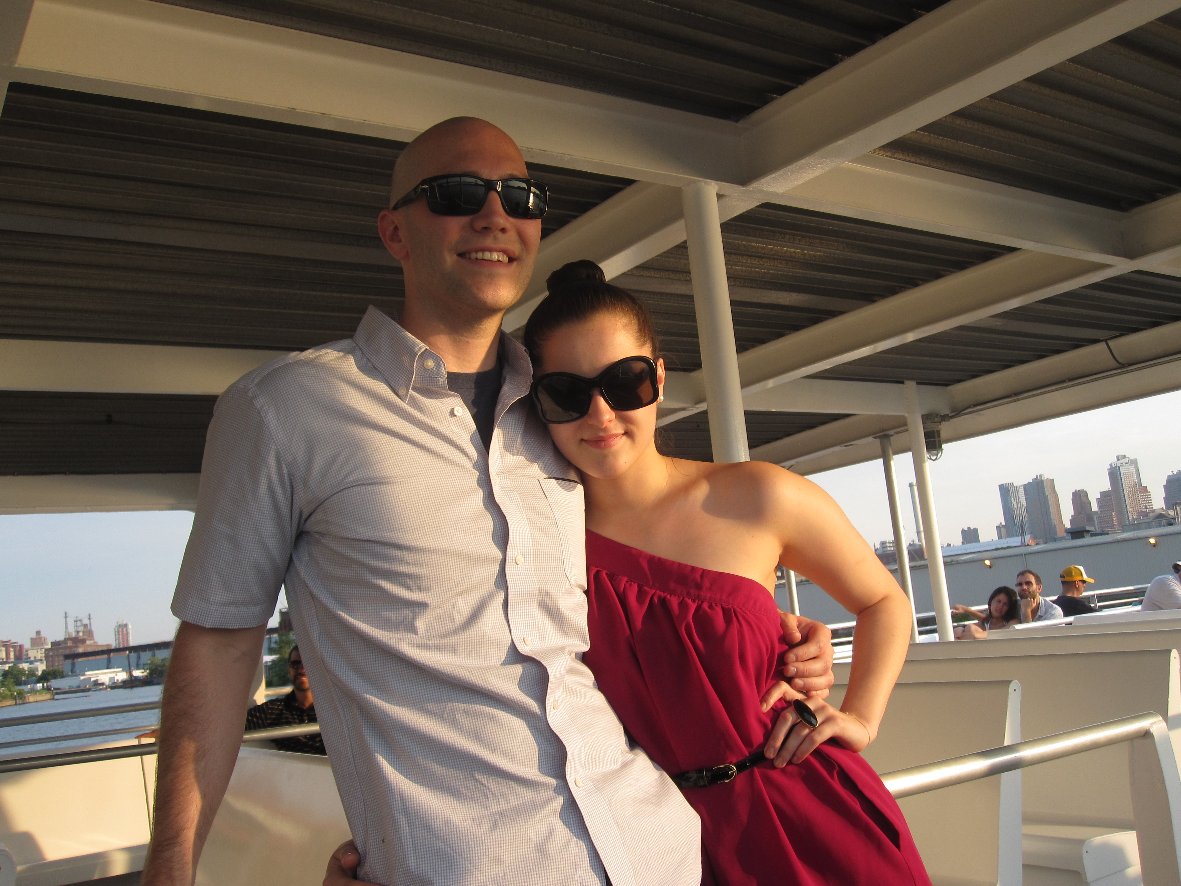 Chris and Amanda on a boat at sunset, NYC skyline behind
